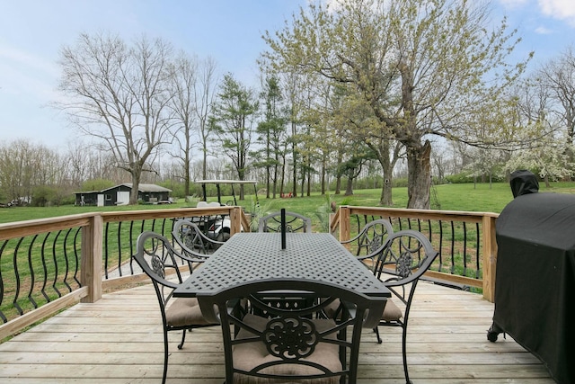 wooden terrace featuring outdoor dining space, an outdoor structure, area for grilling, and a lawn