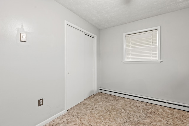 unfurnished bedroom featuring a closet, a baseboard heating unit, and a textured ceiling