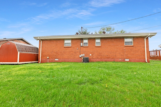 back of house featuring brick siding, a yard, crawl space, a storage unit, and an outbuilding