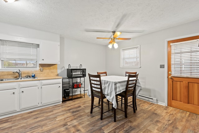 dining area with baseboard heating, a textured ceiling, light wood finished floors, and ceiling fan