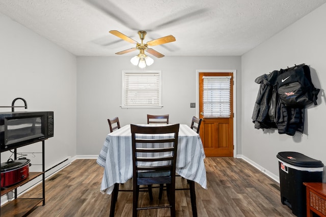 dining room featuring ceiling fan, a textured ceiling, baseboards, and dark wood finished floors