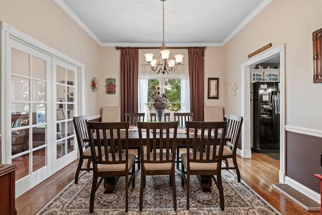 dining area featuring wood finished floors, a notable chandelier, and crown molding