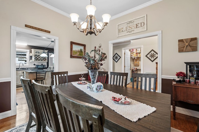dining space with an inviting chandelier, light wood finished floors, ornamental molding, and baseboards