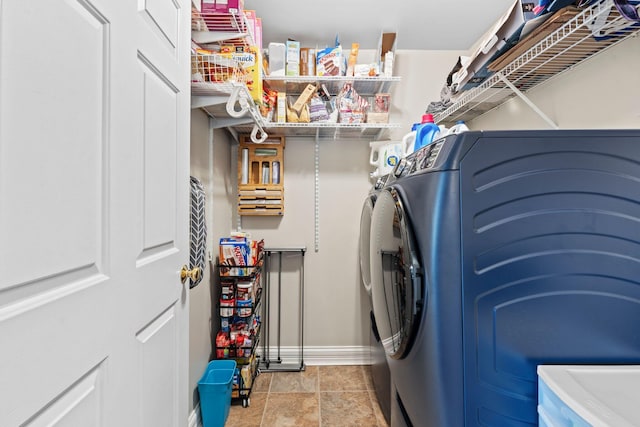 laundry area featuring separate washer and dryer, stone finish floor, laundry area, and baseboards