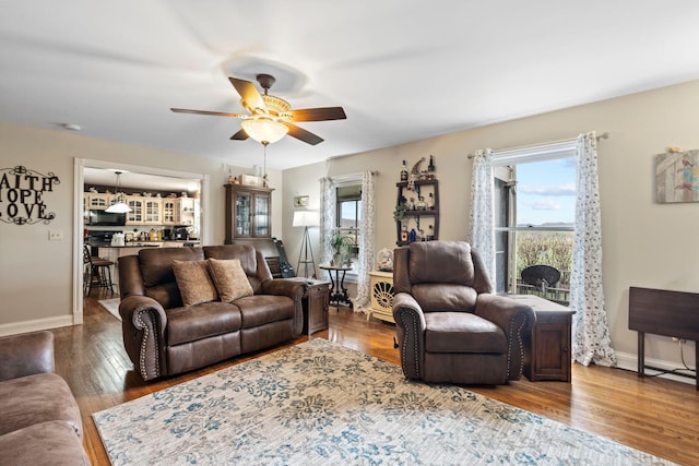 living room featuring wood finished floors, a ceiling fan, and baseboards
