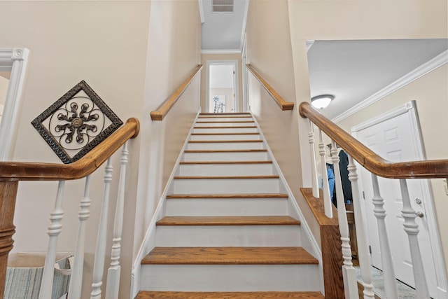stairs with visible vents and crown molding