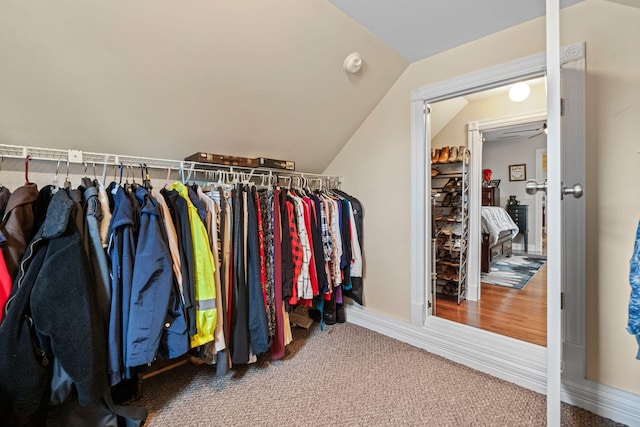 walk in closet with a ceiling fan, carpet flooring, and vaulted ceiling
