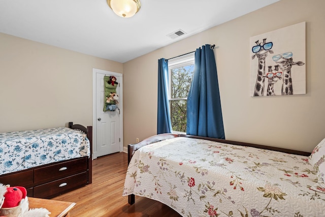 bedroom with visible vents, light wood-type flooring, and baseboards