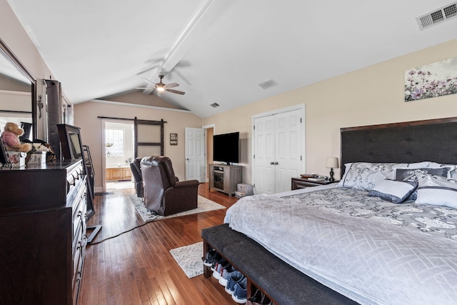 bedroom featuring visible vents, hardwood / wood-style flooring, and a barn door