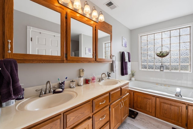 bathroom featuring double vanity, visible vents, a bath, and a sink