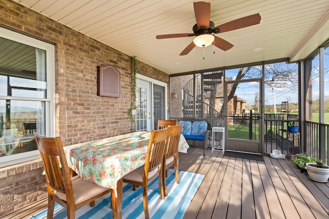 sunroom / solarium with outdoor dining area and a ceiling fan