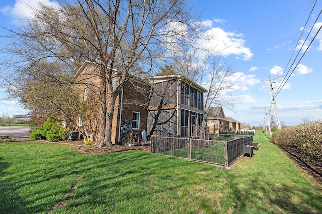 view of side of home featuring fence, a yard, and a sunroom