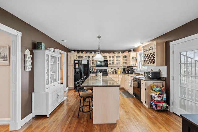 kitchen featuring black appliances, a kitchen breakfast bar, a sink, and a healthy amount of sunlight
