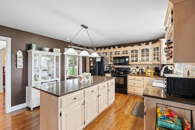 kitchen featuring light wood-type flooring, black appliances, a center island, and a sink