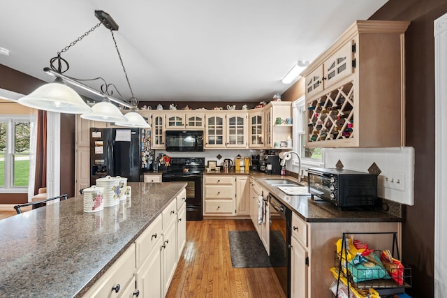 kitchen with black appliances, a healthy amount of sunlight, light wood finished floors, and a sink