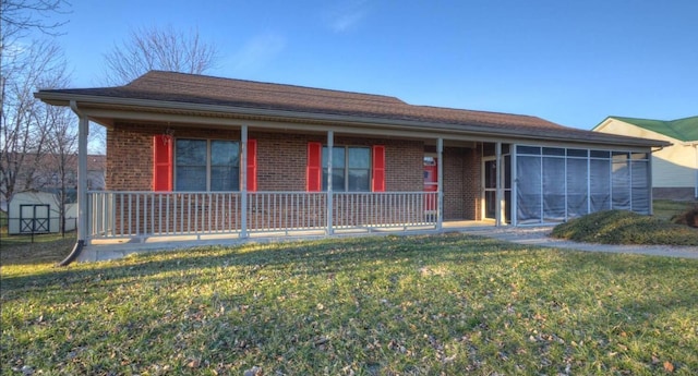 ranch-style house featuring a front yard, brick siding, a sunroom, and covered porch