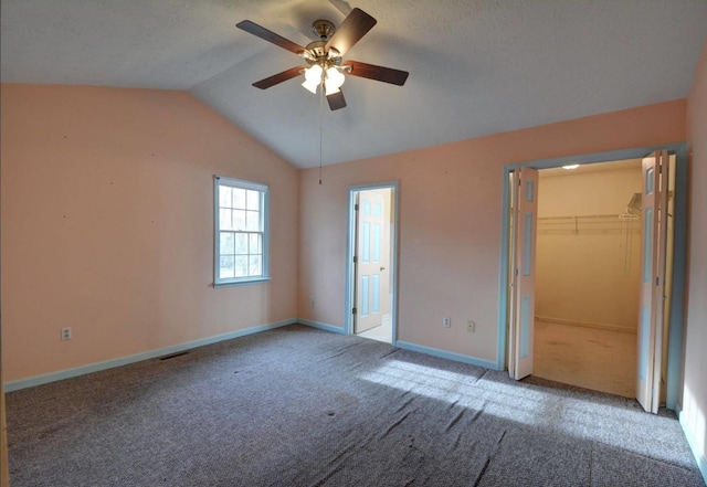 unfurnished bedroom featuring baseboards, vaulted ceiling, a ceiling fan, visible vents, and carpet