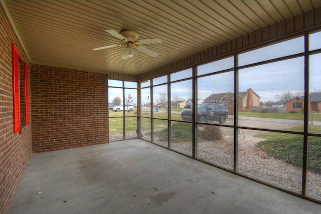 unfurnished sunroom with a ceiling fan and a residential view