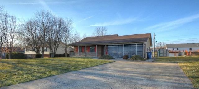 ranch-style house featuring a sunroom, an outdoor structure, and a front lawn