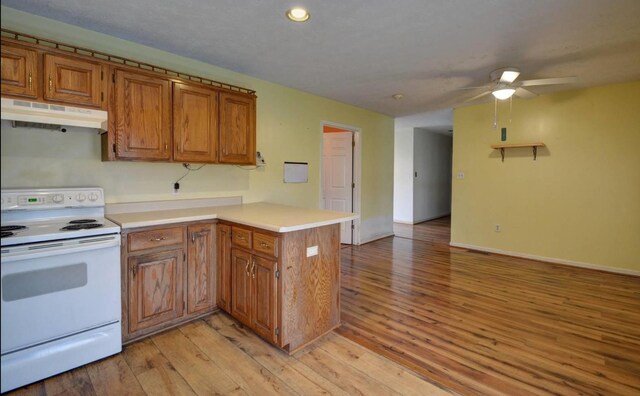 kitchen with ceiling fan, white range with electric cooktop, brown cabinetry, a peninsula, and under cabinet range hood