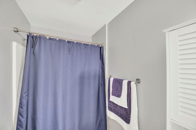 bathroom featuring a textured ceiling and curtained shower