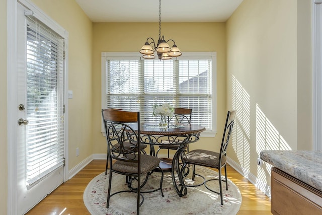 dining space with light wood-type flooring, plenty of natural light, and a notable chandelier
