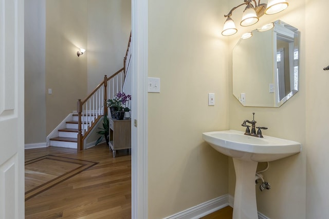 bathroom with a chandelier, baseboards, a sink, and wood finished floors