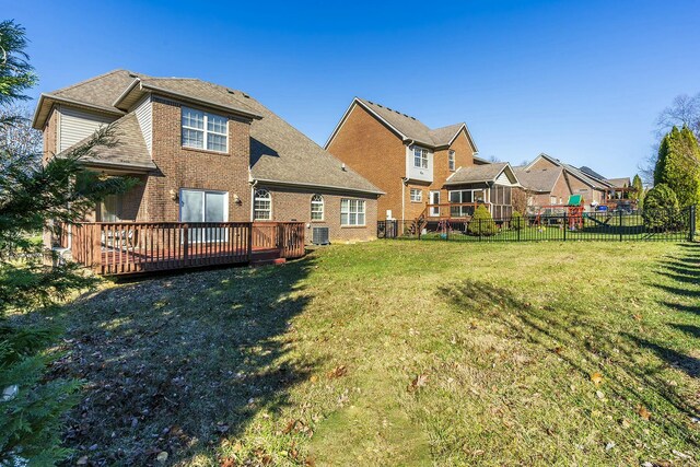 back of property featuring a yard, brick siding, fence, and a deck