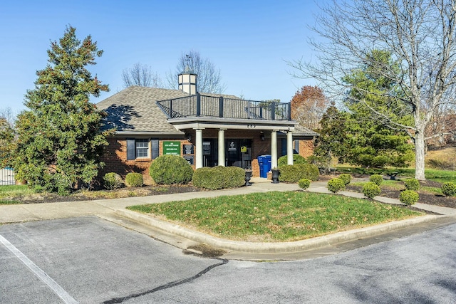 view of front facade with roof with shingles, a front lawn, and brick siding