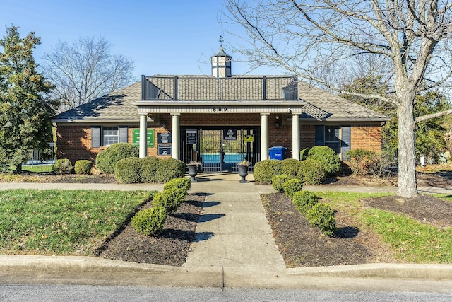 exterior space featuring brick siding and roof with shingles