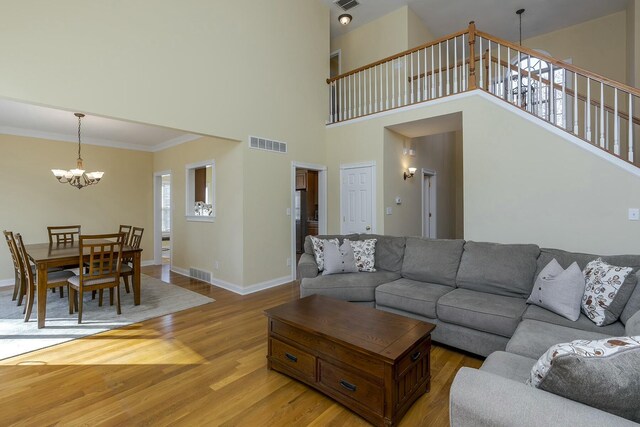 living room featuring visible vents, light wood-style flooring, an inviting chandelier, and baseboards