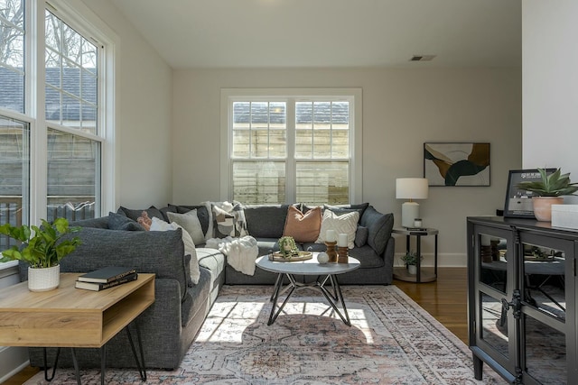 living area with wood finished floors, baseboards, and visible vents