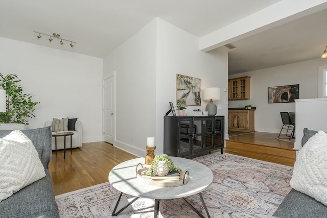 living area featuring rail lighting, visible vents, baseboards, and wood finished floors