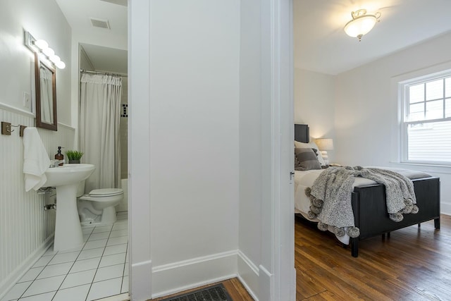 bedroom featuring visible vents, light wood-type flooring, and connected bathroom