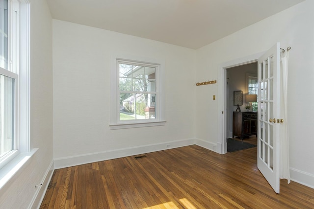 spare room with wood finished floors, baseboards, and visible vents