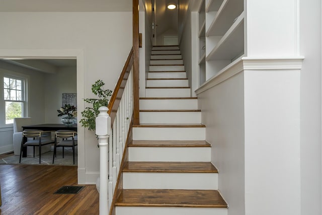 staircase featuring visible vents, baseboards, and wood finished floors