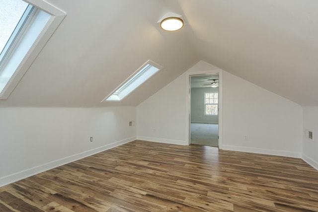 bonus room featuring baseboards, lofted ceiling with skylight, and wood finished floors