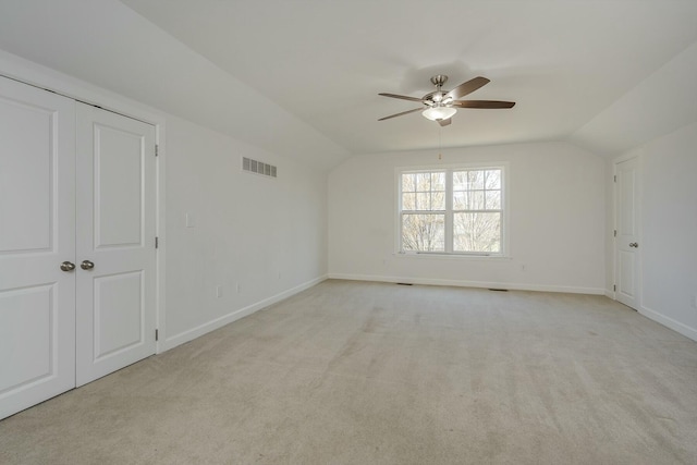 empty room featuring baseboards, visible vents, vaulted ceiling, and a ceiling fan