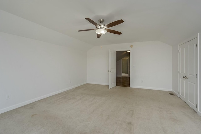 unfurnished bedroom featuring light carpet, baseboards, a ceiling fan, and vaulted ceiling