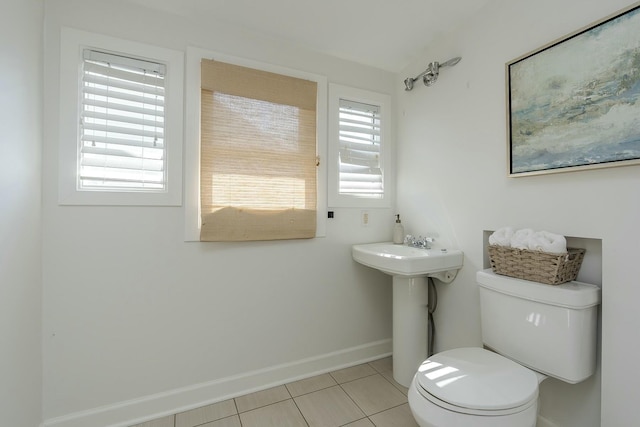 half bathroom featuring toilet, tile patterned floors, a sink, and baseboards