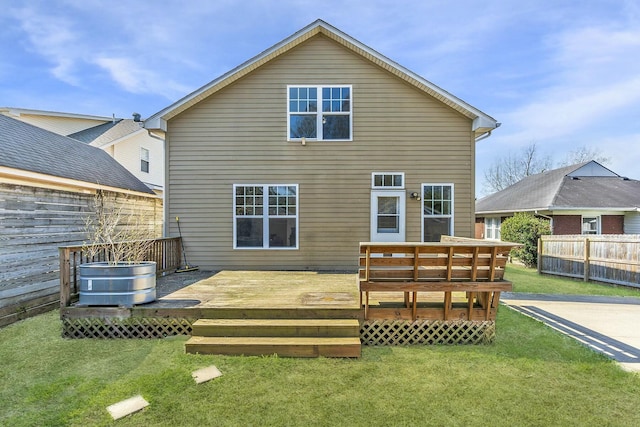 rear view of property with a wooden deck, fence, and a lawn