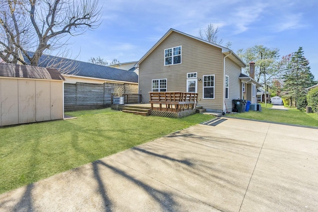 rear view of property featuring central AC unit, a yard, a storage shed, an outdoor structure, and a wooden deck