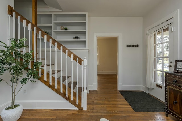 foyer entrance with stairway, baseboards, and wood finished floors
