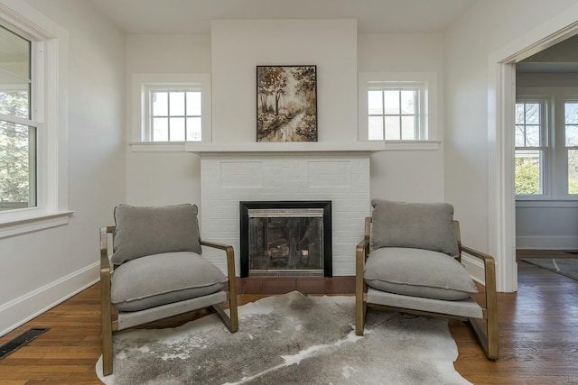 sitting room featuring a fireplace, visible vents, baseboards, and wood finished floors