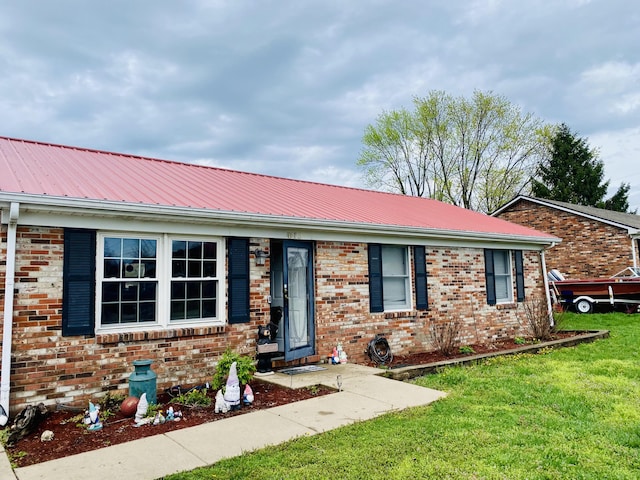 ranch-style home with metal roof, a front lawn, and brick siding