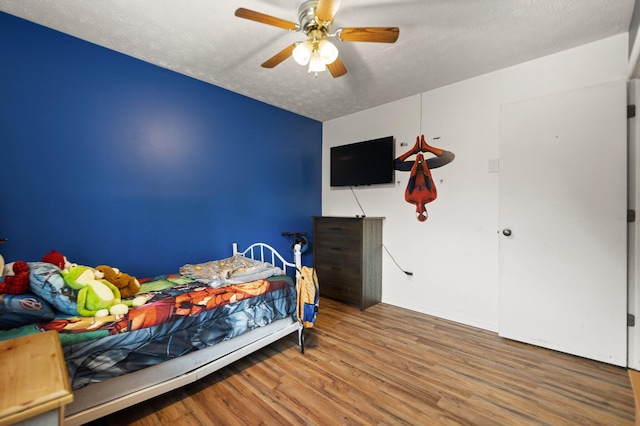 bedroom featuring a ceiling fan, wood finished floors, and a textured ceiling