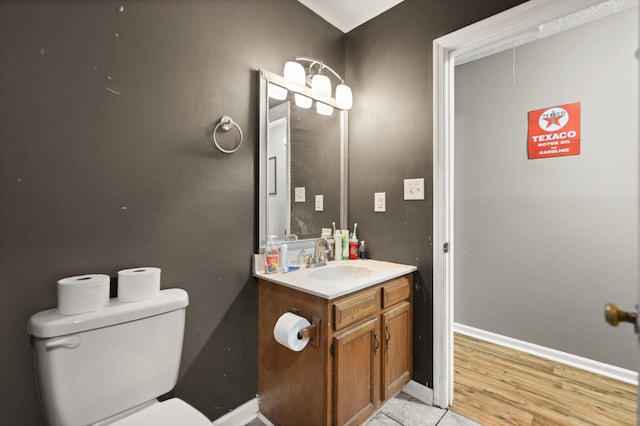 half bath featuring toilet, wood finished floors, vanity, and baseboards