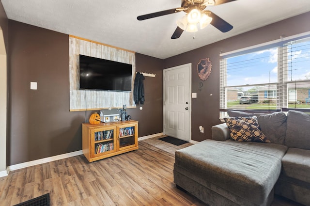 living room with visible vents, baseboards, ceiling fan, and wood finished floors