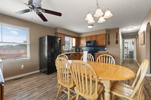 dining room with ceiling fan with notable chandelier, visible vents, attic access, baseboards, and dark wood-style floors