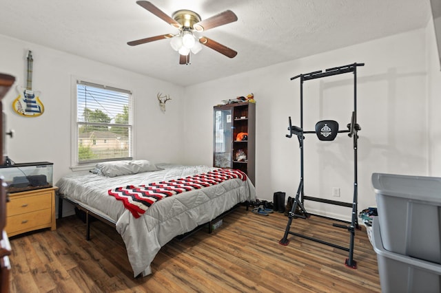 bedroom with baseboards, a ceiling fan, wood finished floors, and a textured ceiling